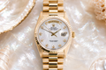 Gold watch with a white face on a textured shell background