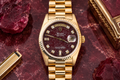 Gold wristwatch with a dark face on a red marbled surface