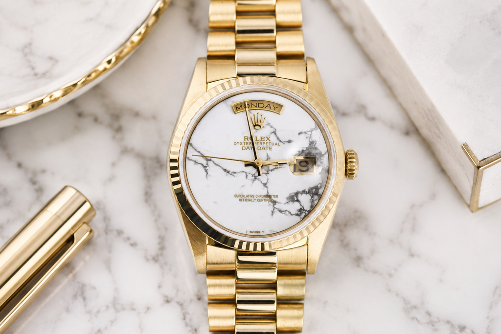 Gold watch with marble face on a marble surface