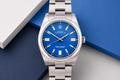 Silver watch with a blue face on a geometric background