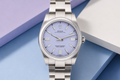 Silver watch with a light blue dial on a blue and purple gradient background