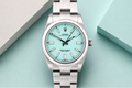 Silver watch with a turquoise dial on a light blue background