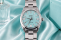 Silver watch with a light blue face on a light blue satin background