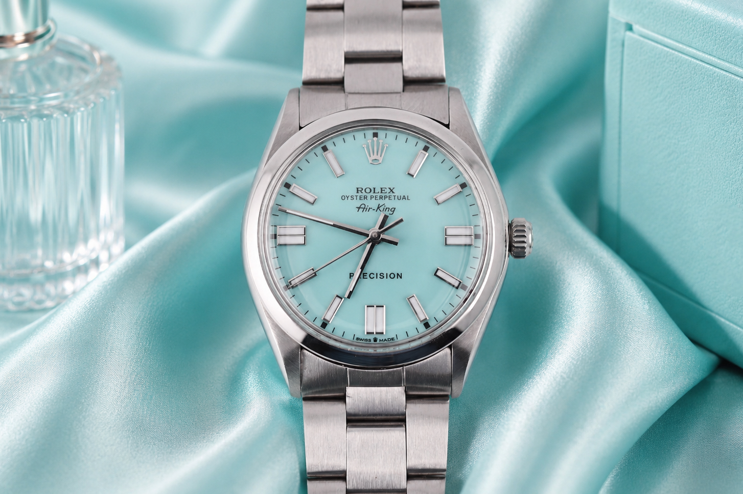 Silver watch with a light blue face on a light blue satin background