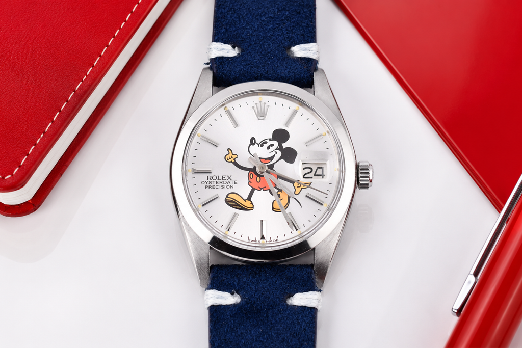 Watch with a blue strap and Mickey Mouse face on the dial, displayed against a red and white background.