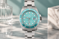 Silver watch with turquoise dial on a marble surface