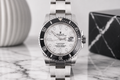 Silver watch with a white face on a marble surface