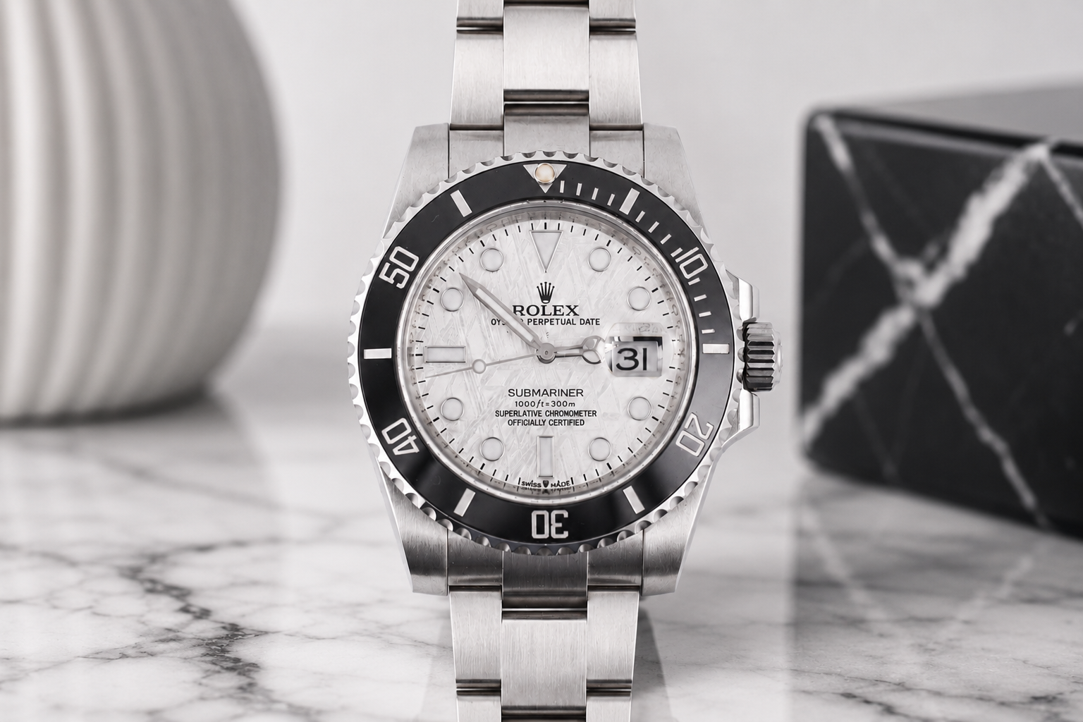 Silver watch with a white face on a marble surface