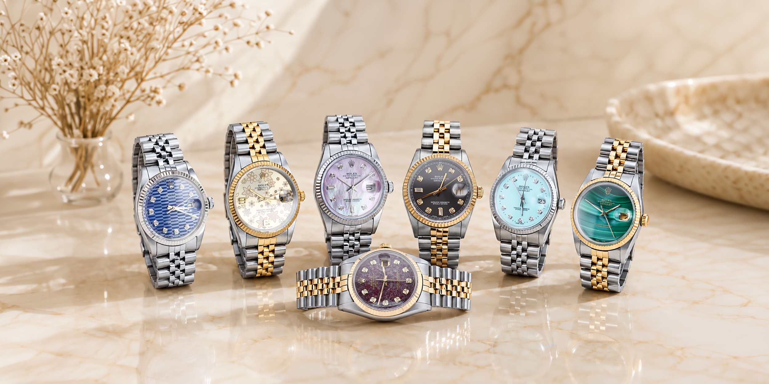 Seven watches with different colored faces and metallic bands on a beige surface.