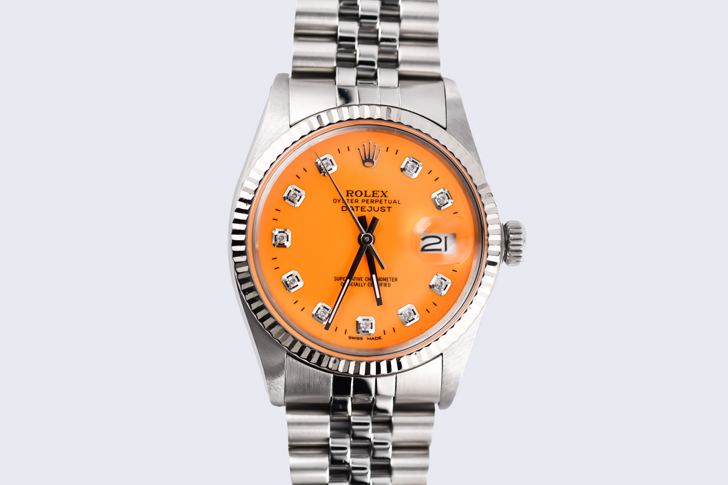 Silver watch with an orange face on a light gray background