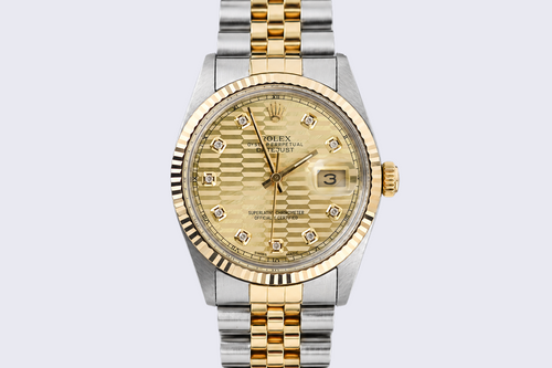 Gold and silver watch with a detailed face on a light gray background