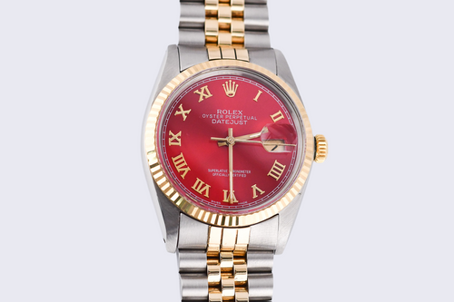 Two-tone watch with a red face on a light gray background
