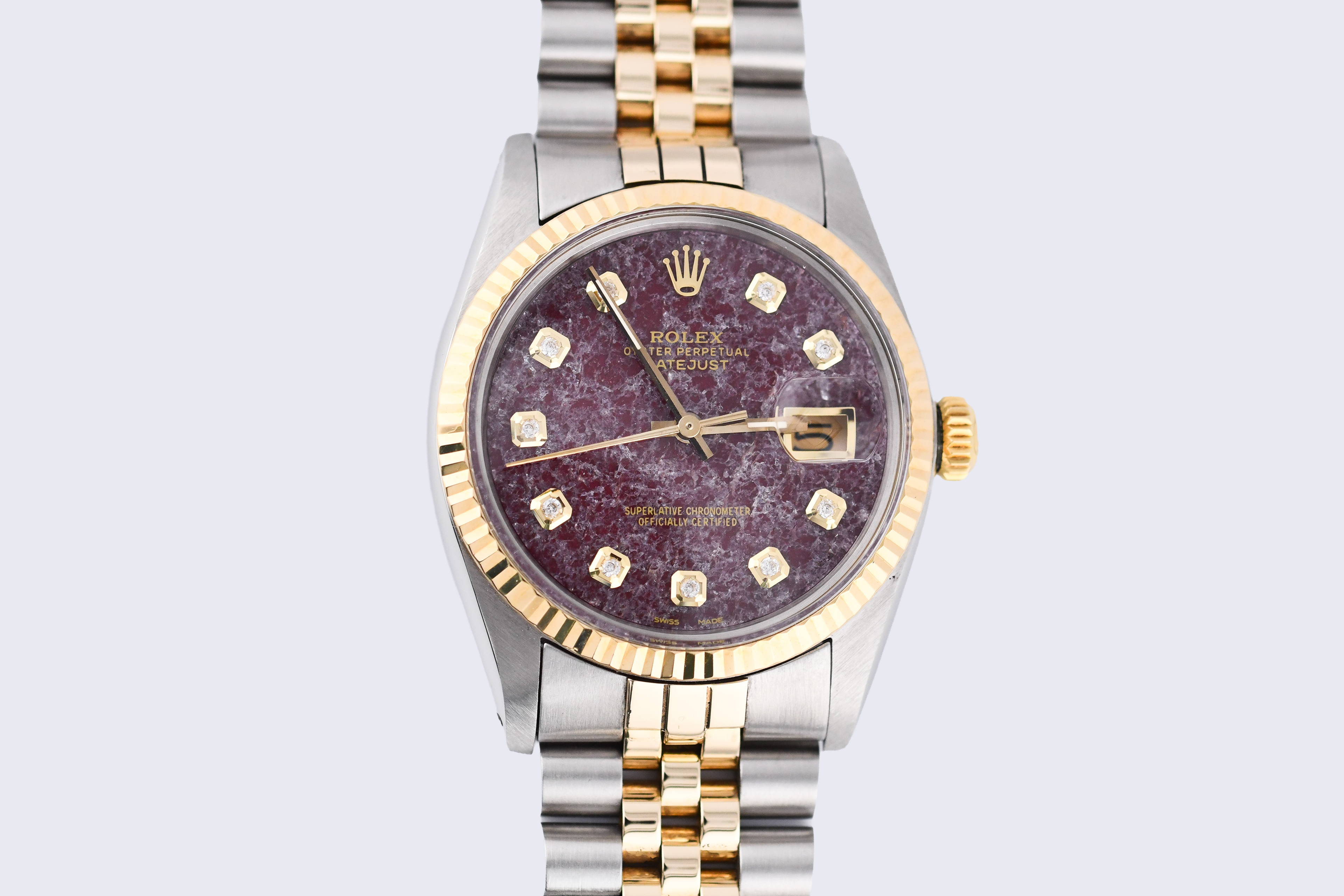 Luxury watch with a purple dial and gold accents on a light gray background