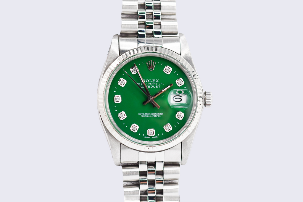 Silver watch with a green dial on a light gray background