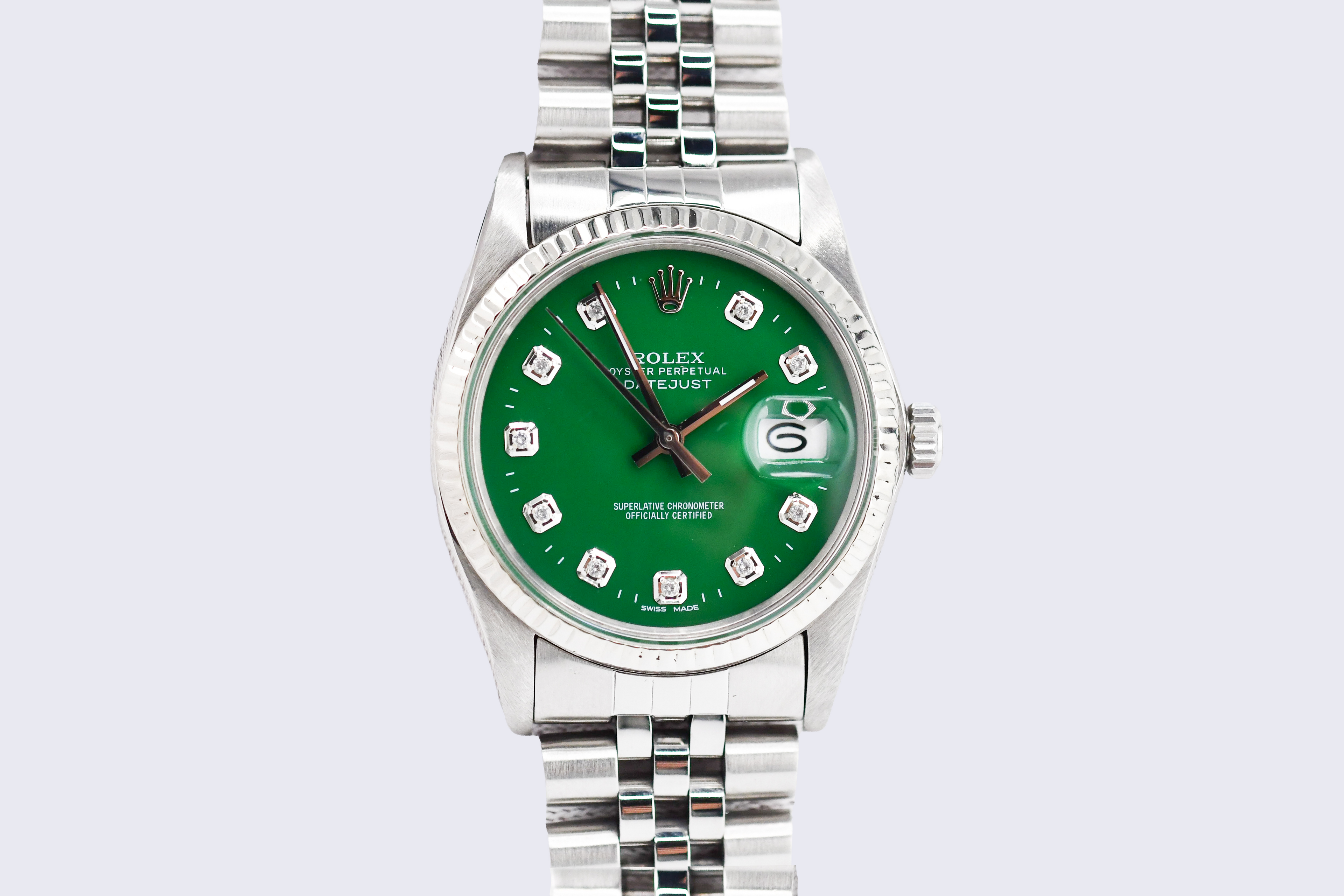 Silver watch with a green dial on a light gray background
