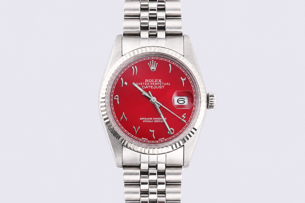 Silver watch with a red face on a light gray background