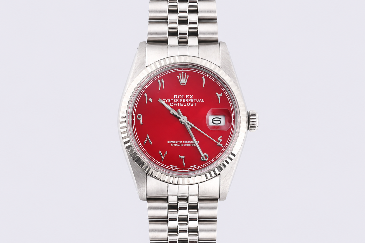Silver watch with a red face on a light gray background