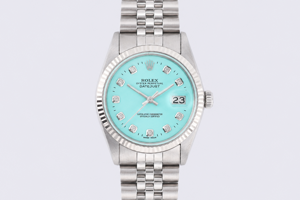 Silver watch with a turquoise dial on a light gray background