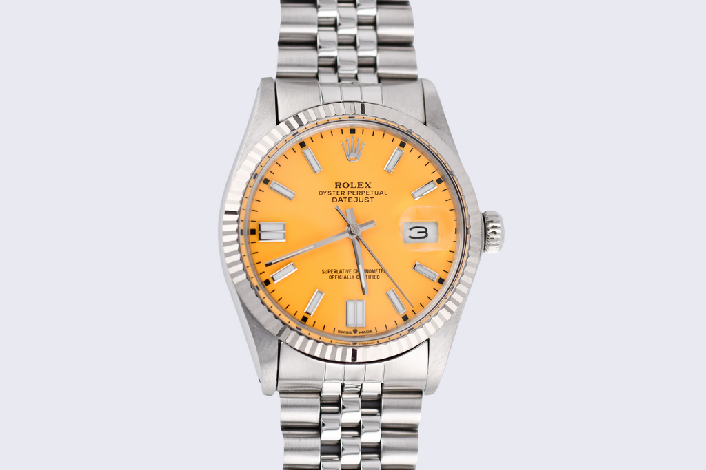 Silver Rolex watch with a orange dial on a light gray background