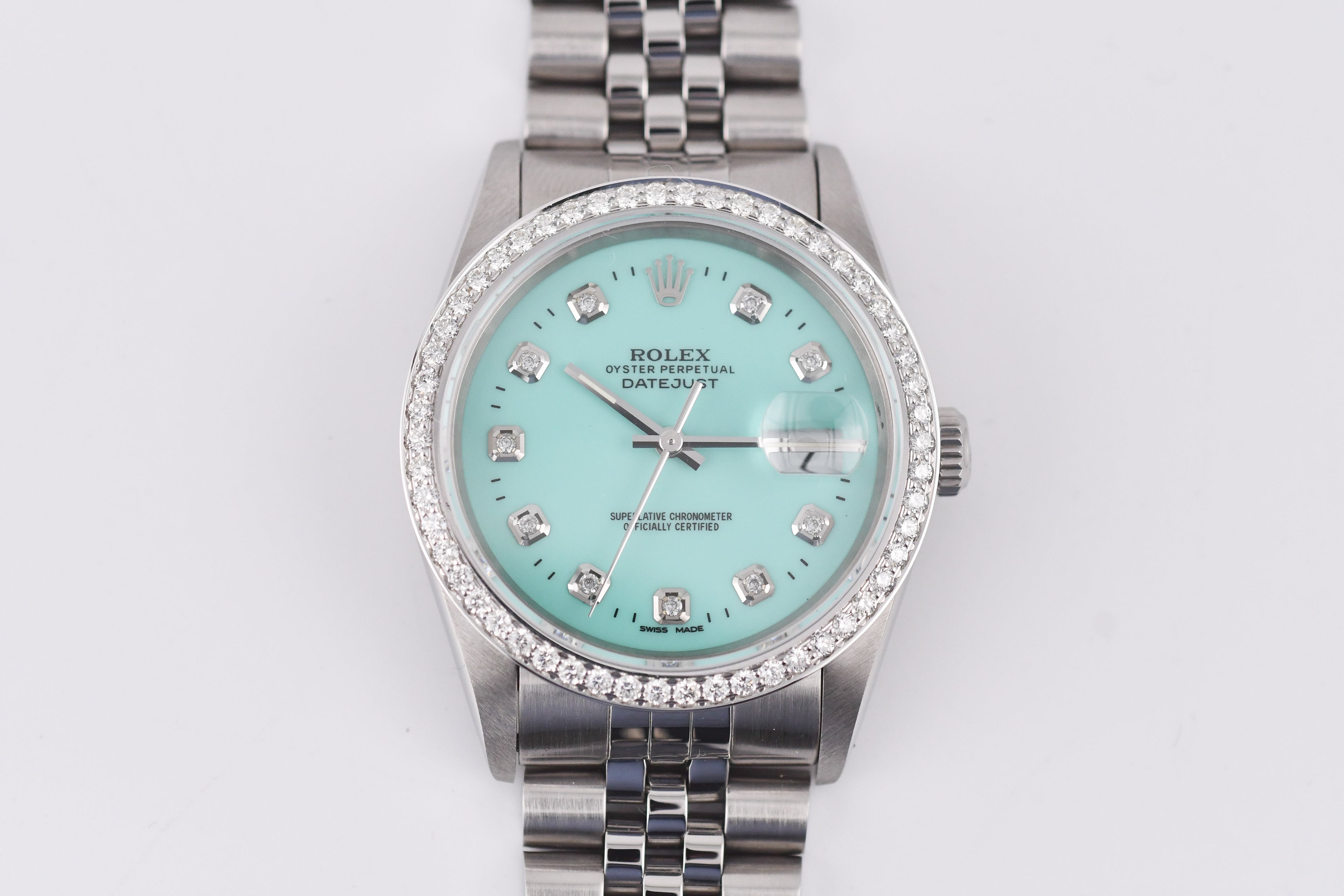 Silver watch with a turquoise dial and diamond accents on a white background