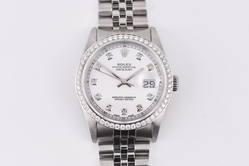 Silver watch with a white face and diamond accents on a light gray background