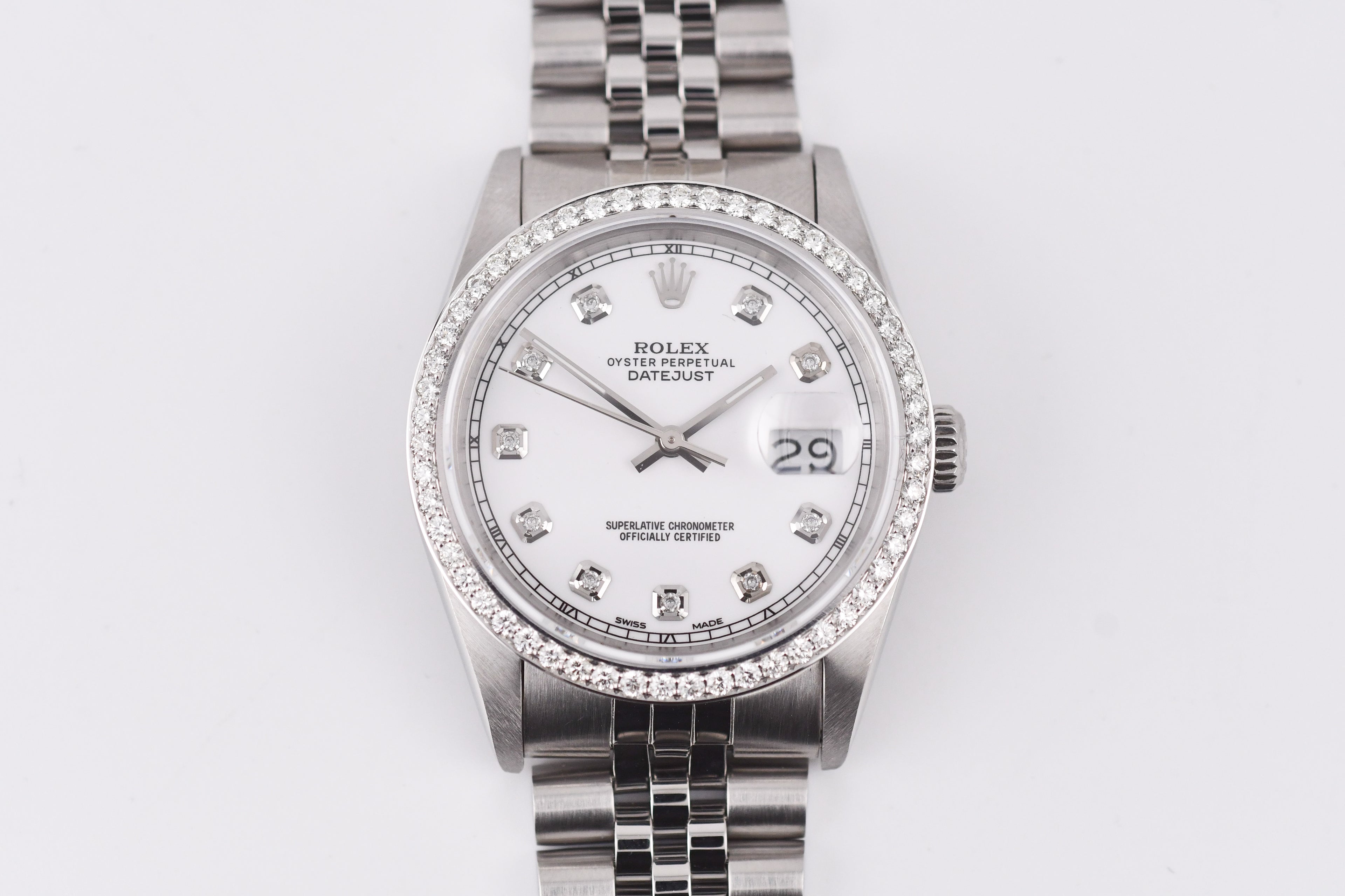 Silver watch with a white face and diamond accents on a light gray background