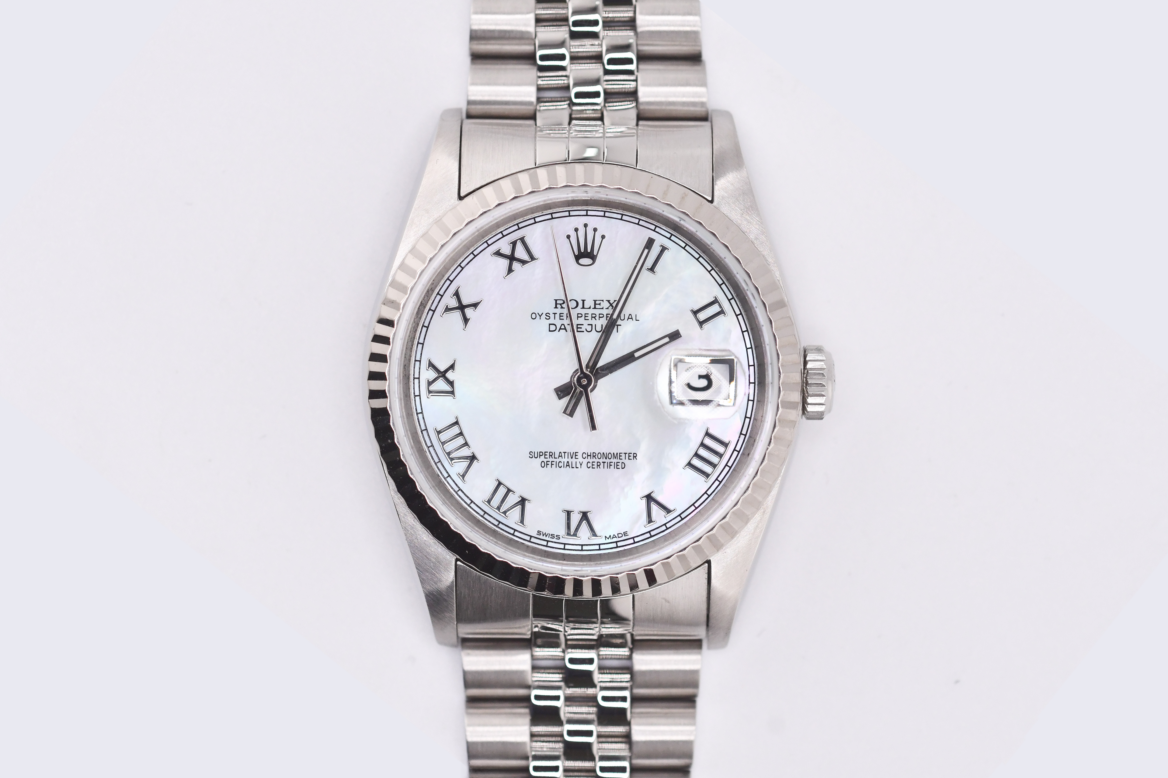 Silver Rolex watch with a white face on a light gray background