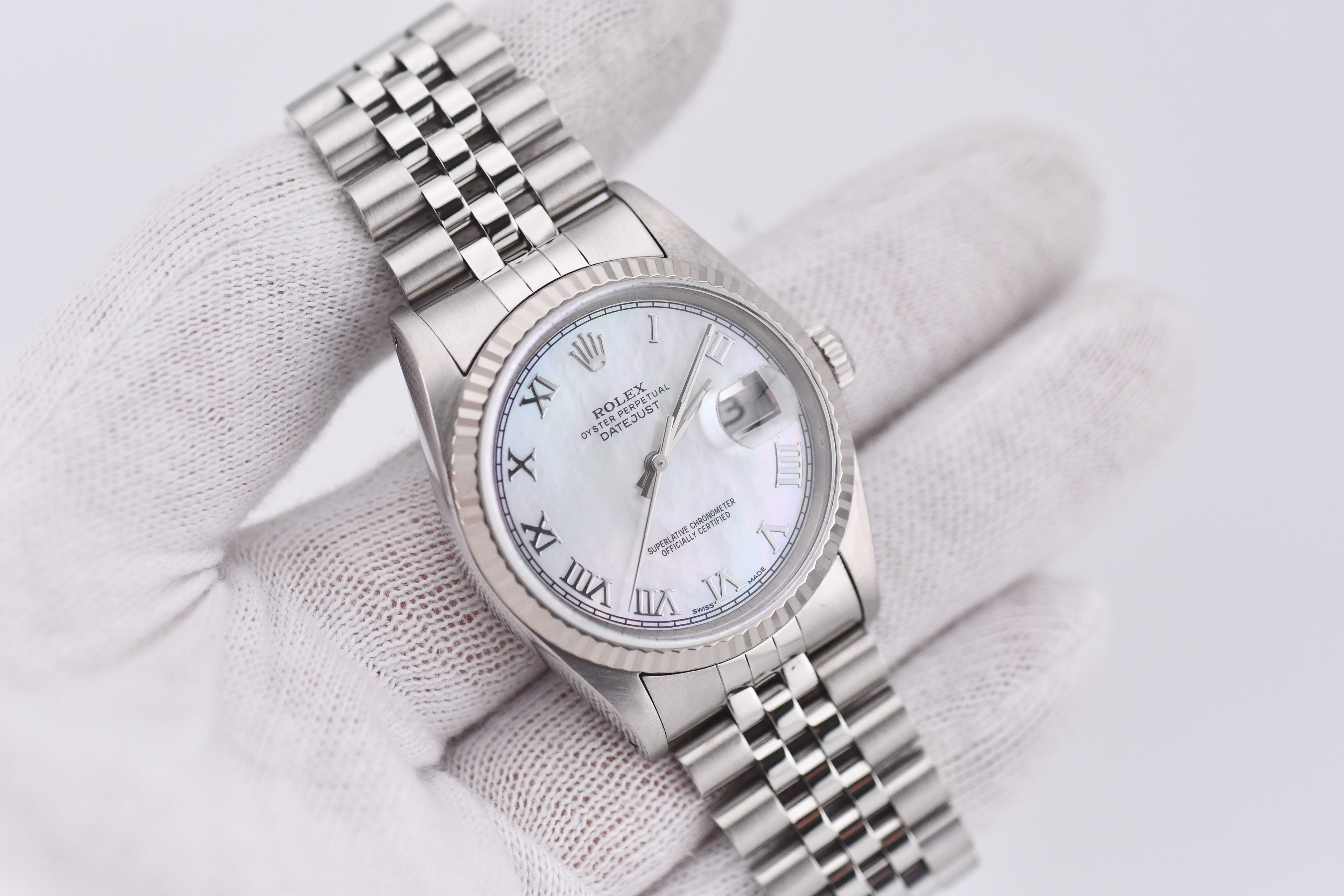 Silver watch with a white face on a light gray background