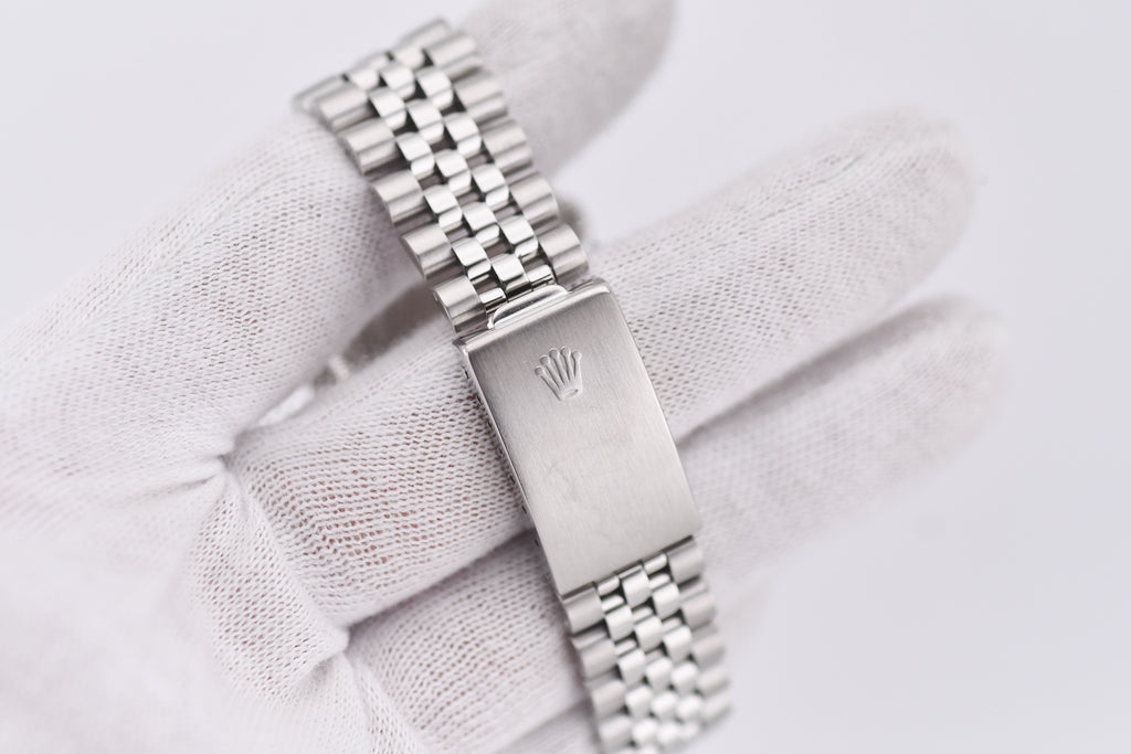 Silver watch with a visible brand logo on a light fabric background