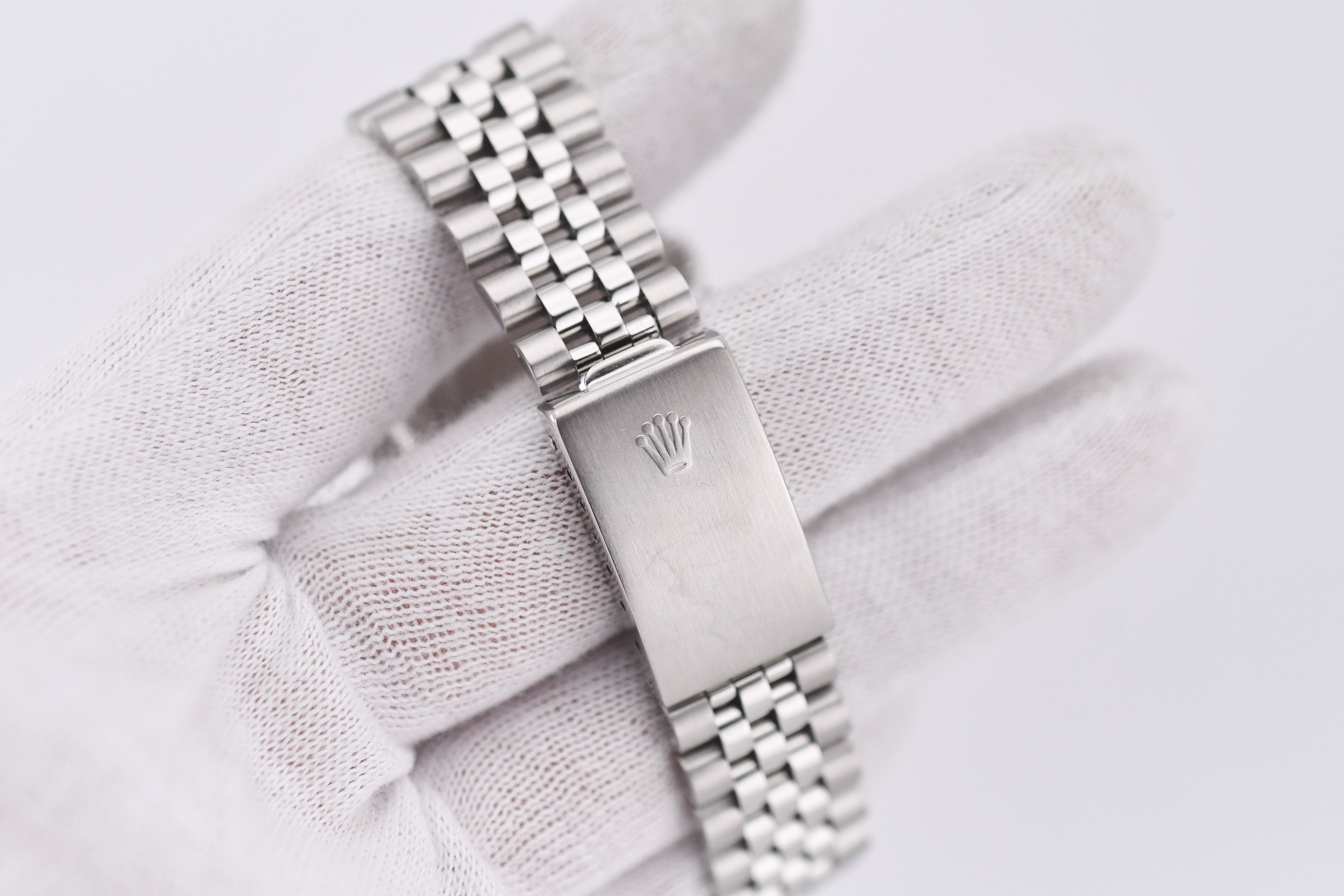 Silver watch with a visible brand logo on a light fabric background
