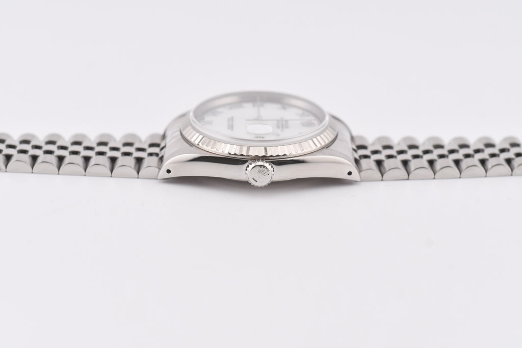 Silver wristwatch with a white face on a light gray background