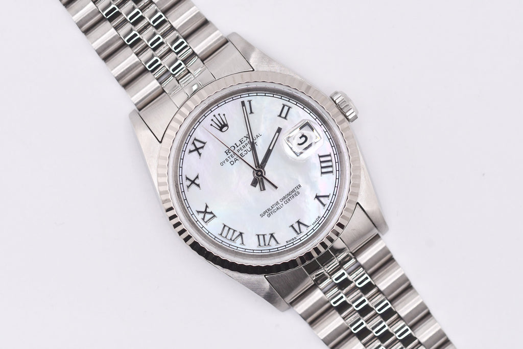 Silver watch with a white face and Roman numerals on a light gray background