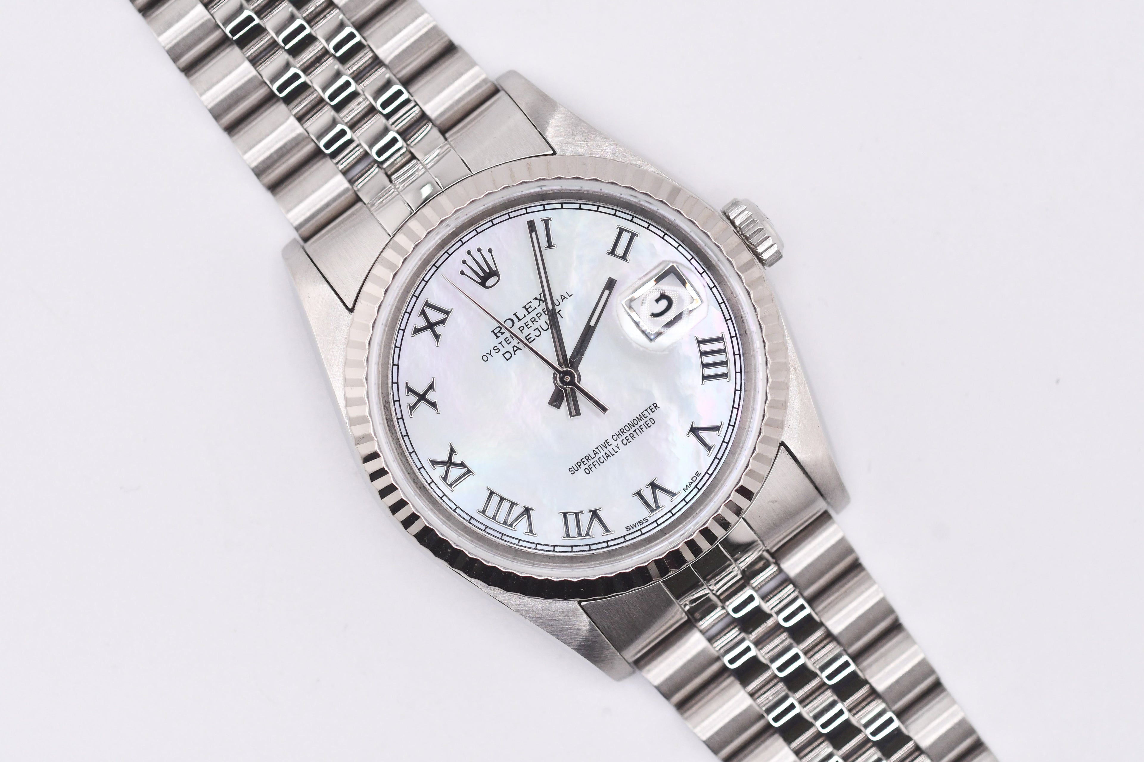 Silver watch with a white face and Roman numerals on a light gray background
