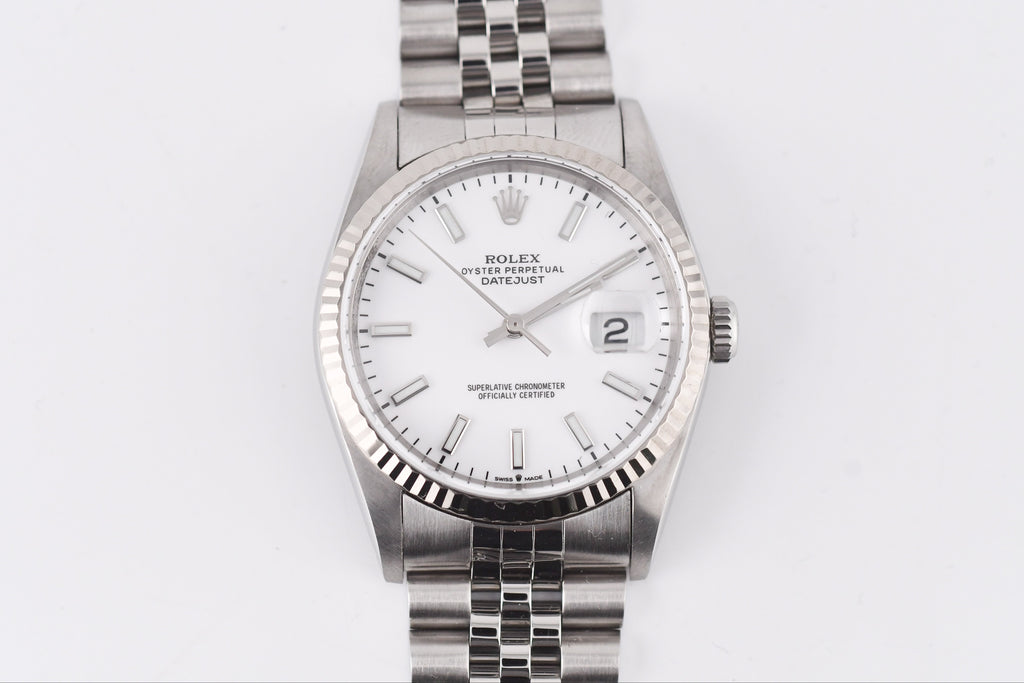 Silver Rolex watch with a white face on a light gray background