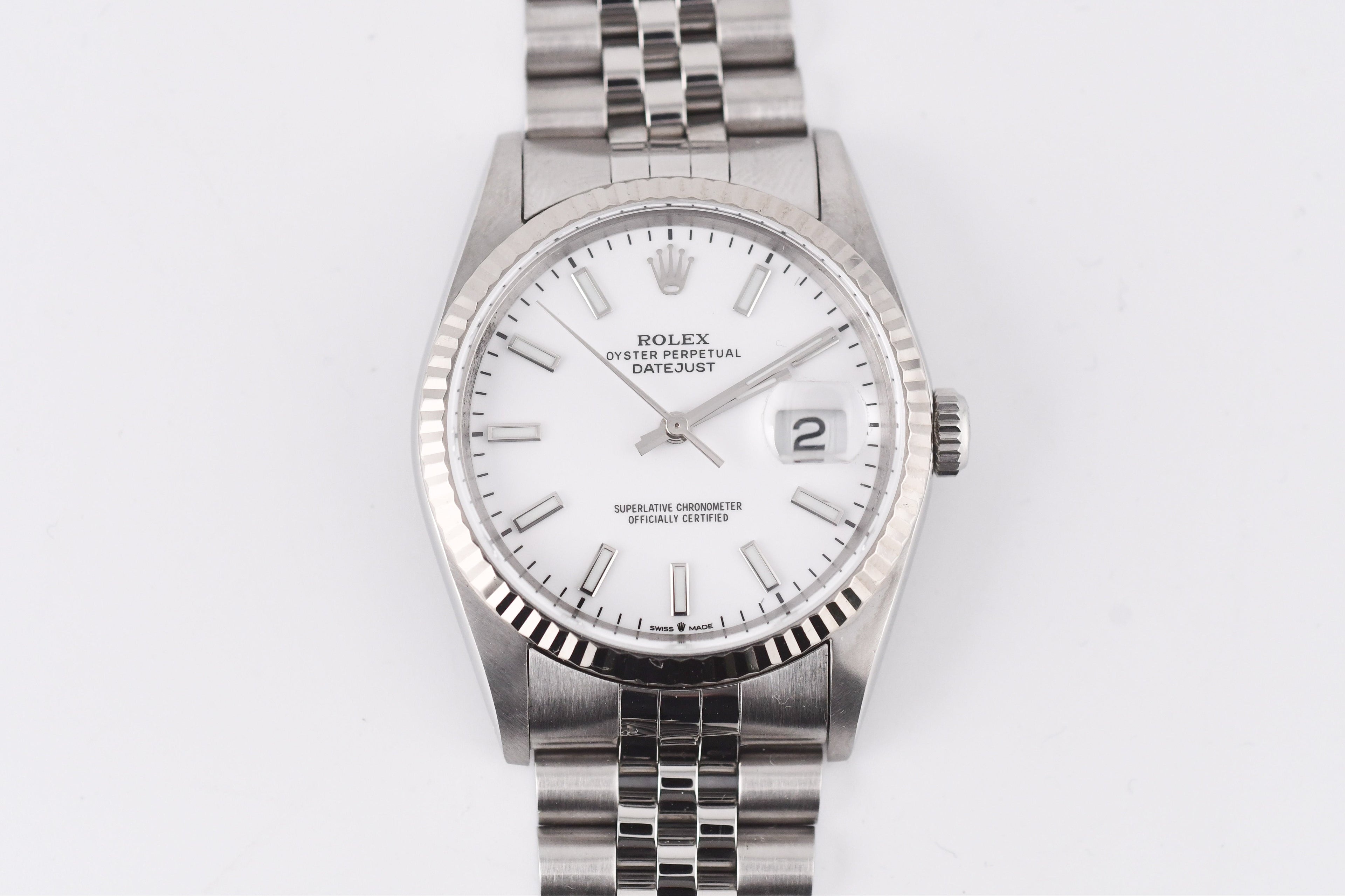 Silver Rolex watch with a white face on a light gray background