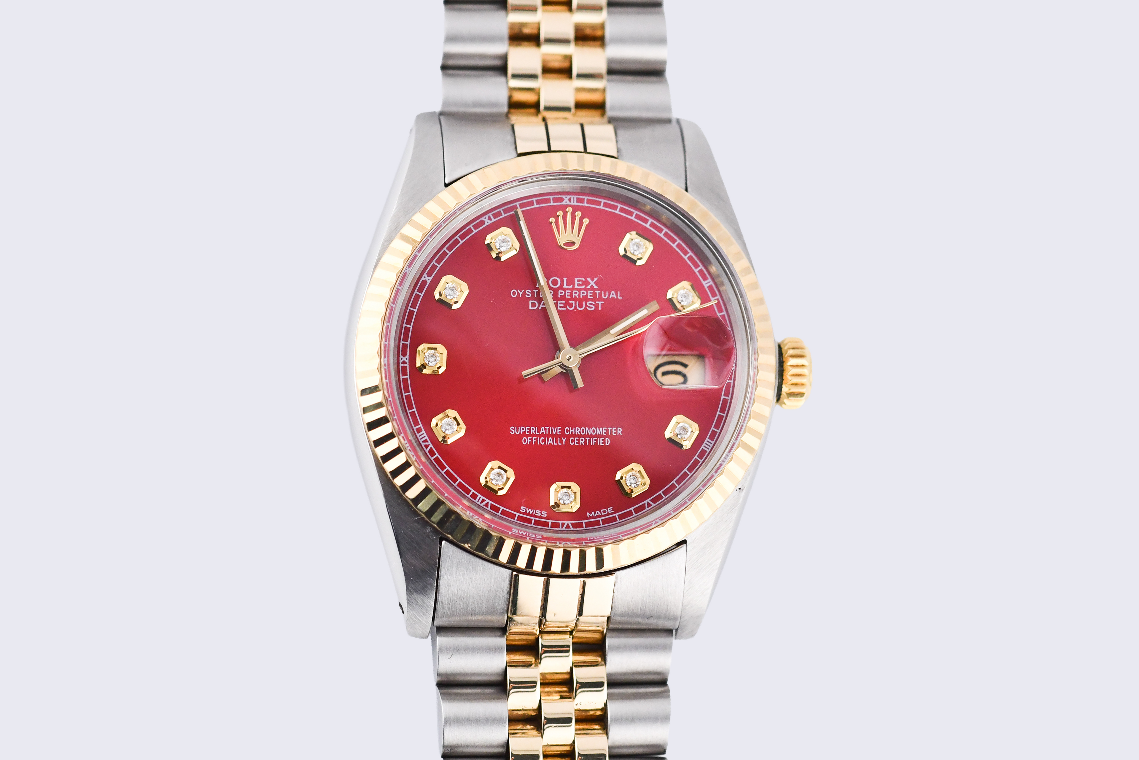 Luxury watch with red face and gold accents on a light gray background