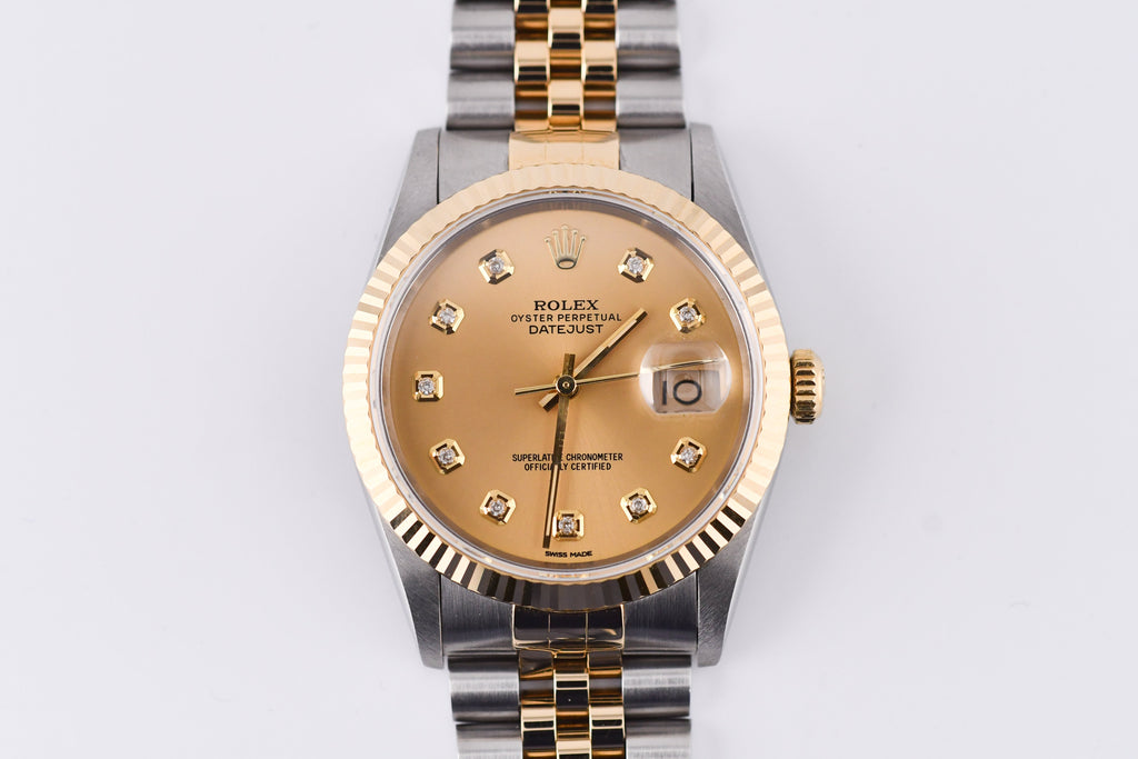 Luxury watch with gold and silver band on a light gray background