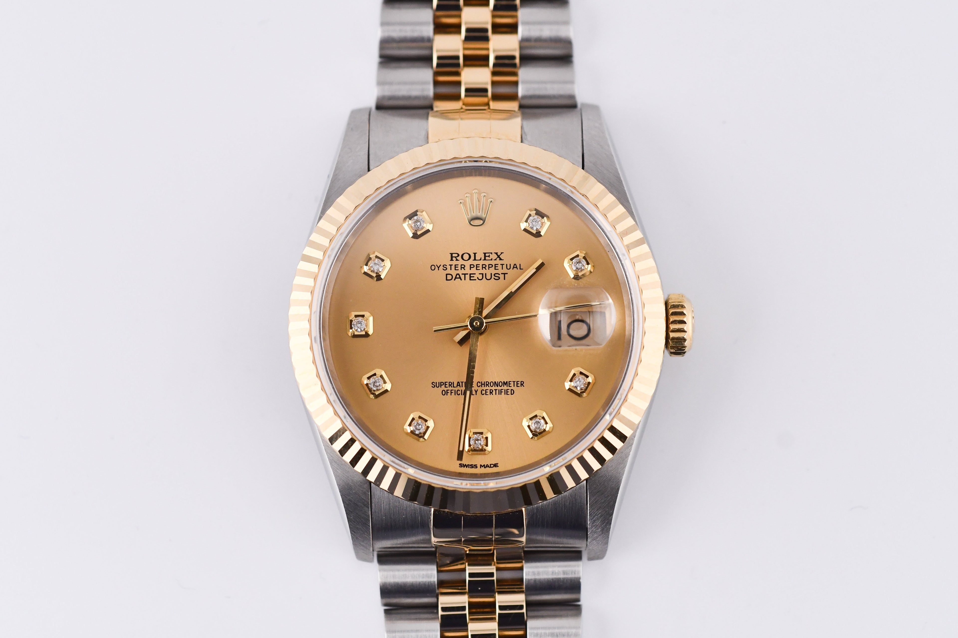 Luxury watch with gold and silver band on a light gray background