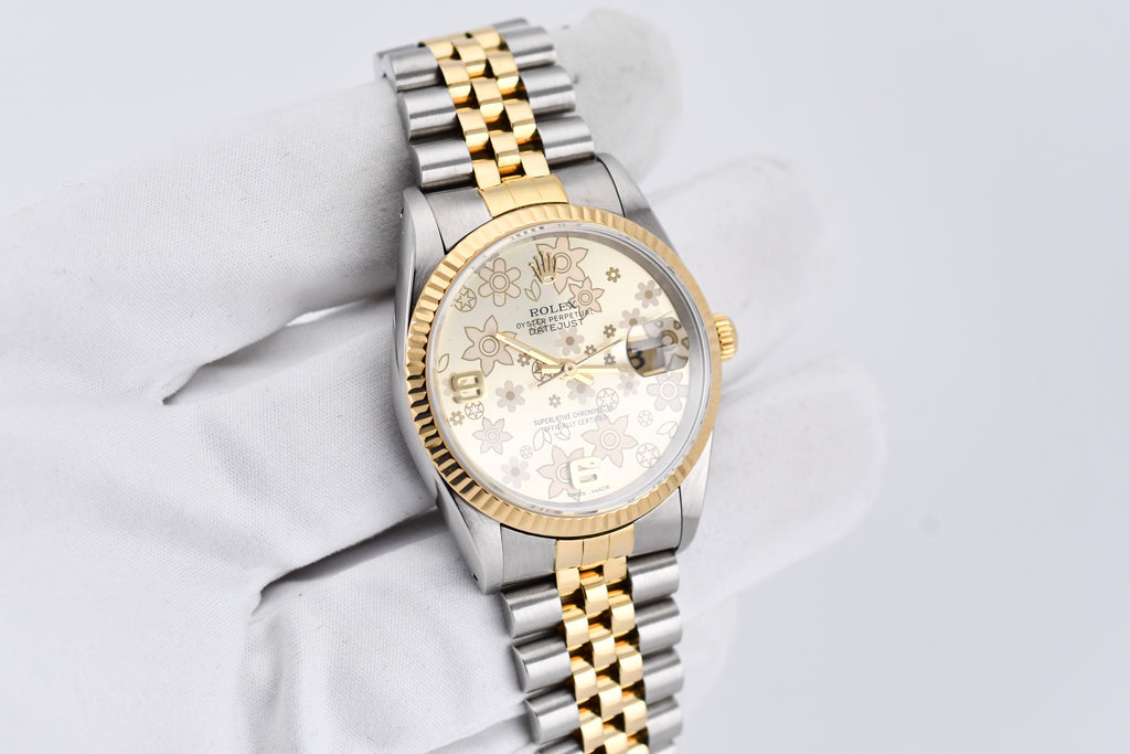Luxury watch with gold and silver band on a light gray background