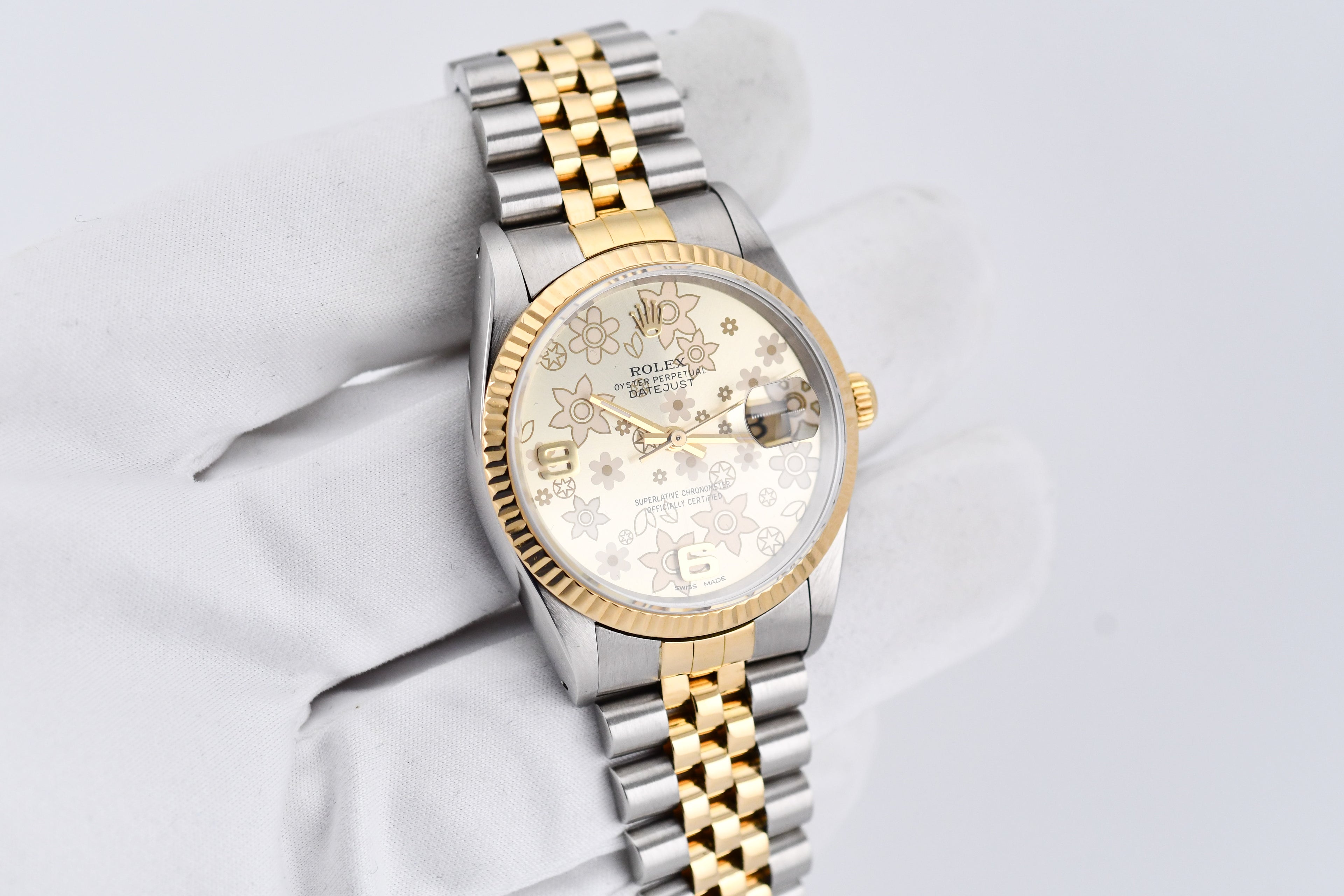Luxury watch with gold and silver band on a light gray background