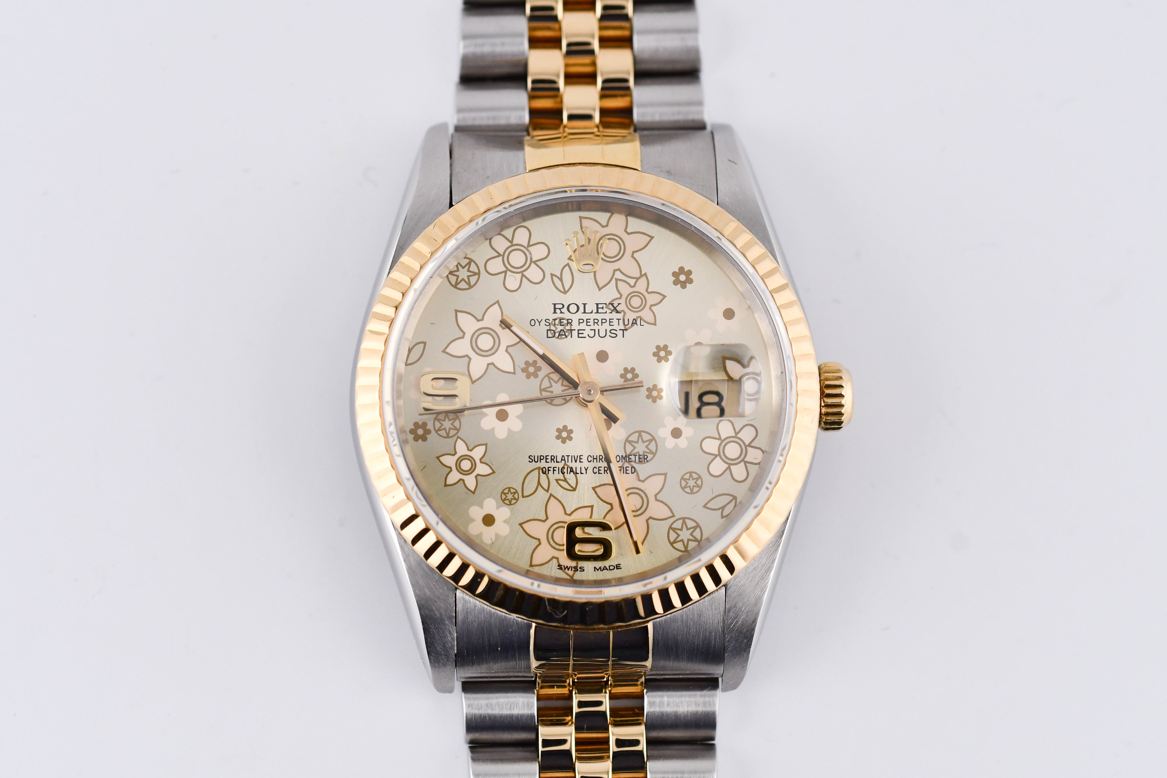 Two-tone watch with floral patterned face on a light gray background