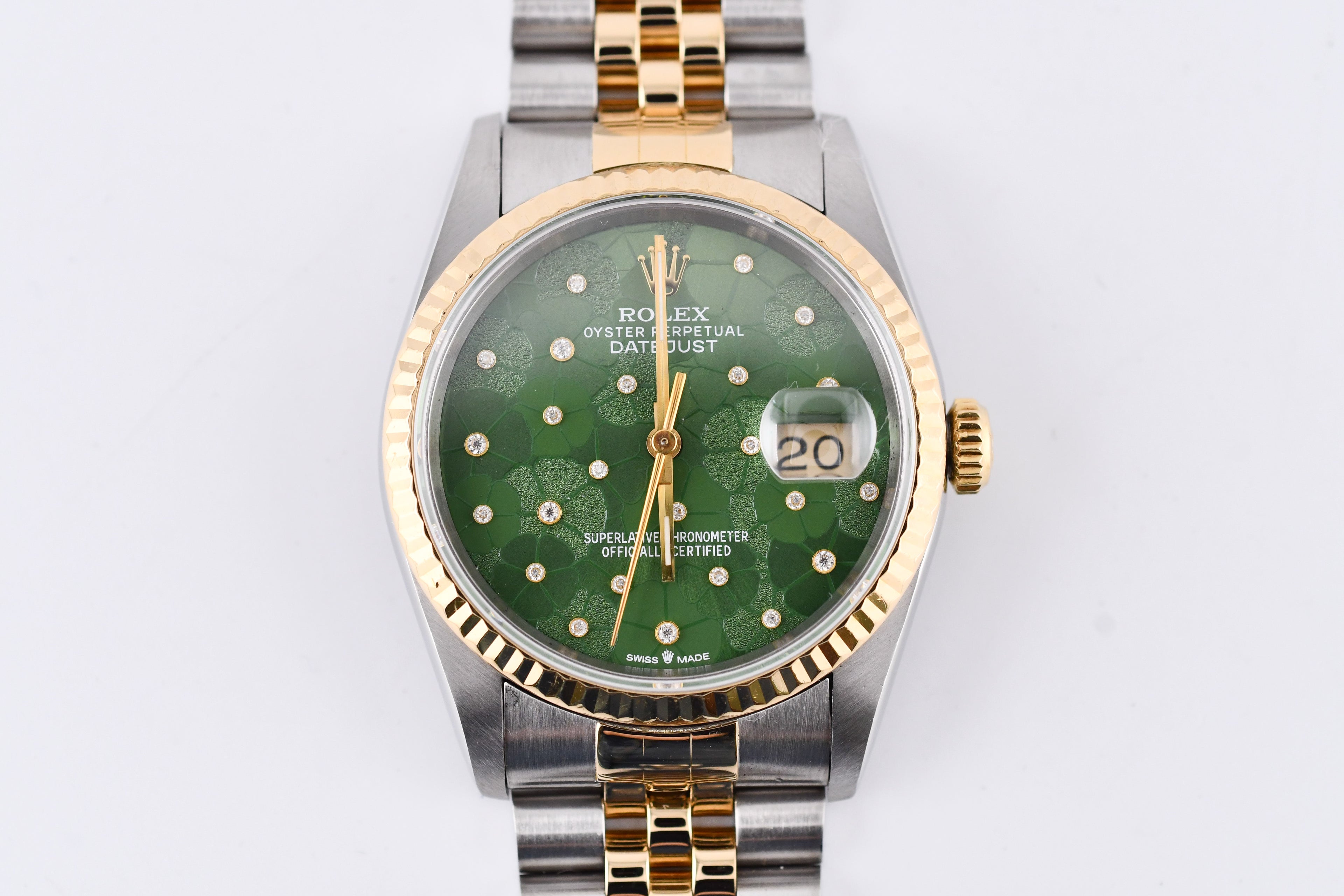 Rolex watch with green dial and gold and silver band on a white background