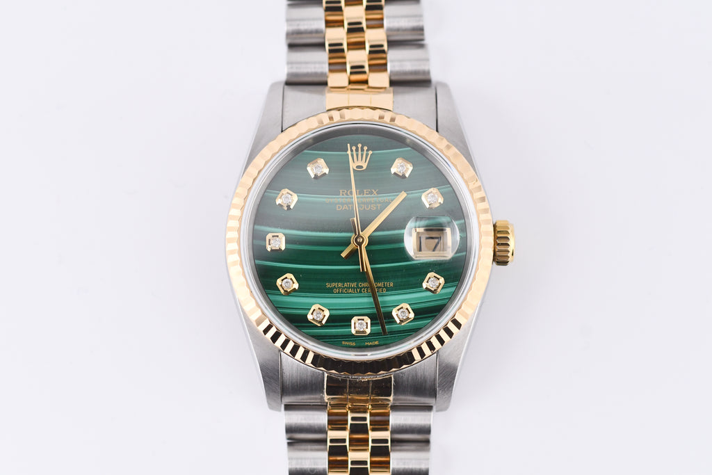 Luxury watch with green face and gold accents on a white background