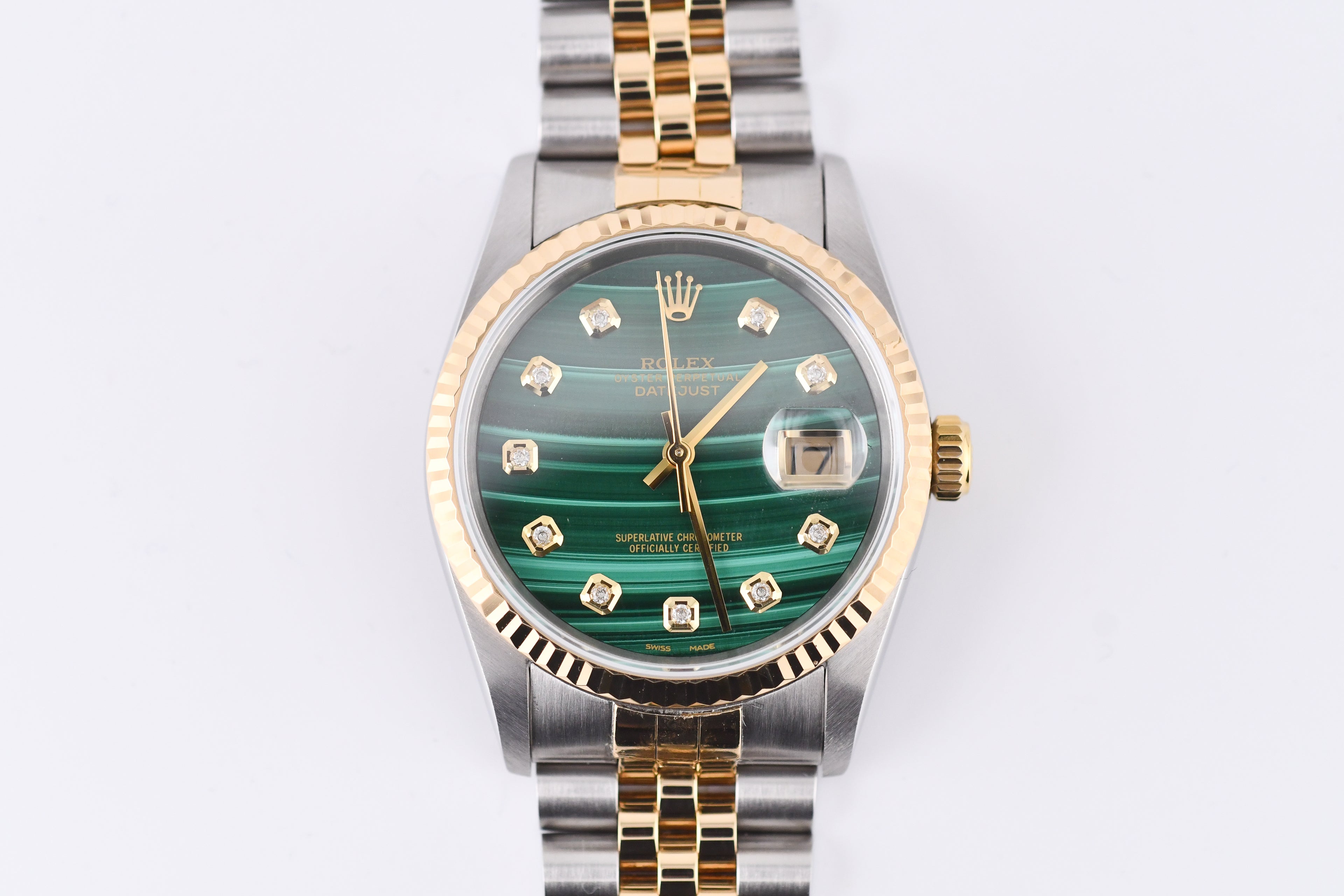 Luxury watch with green face and gold accents on a white background