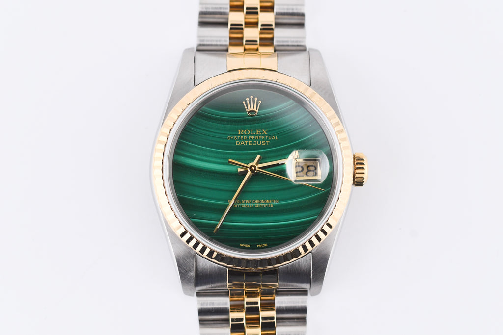 Rolex watch with green face and gold and silver band on white background