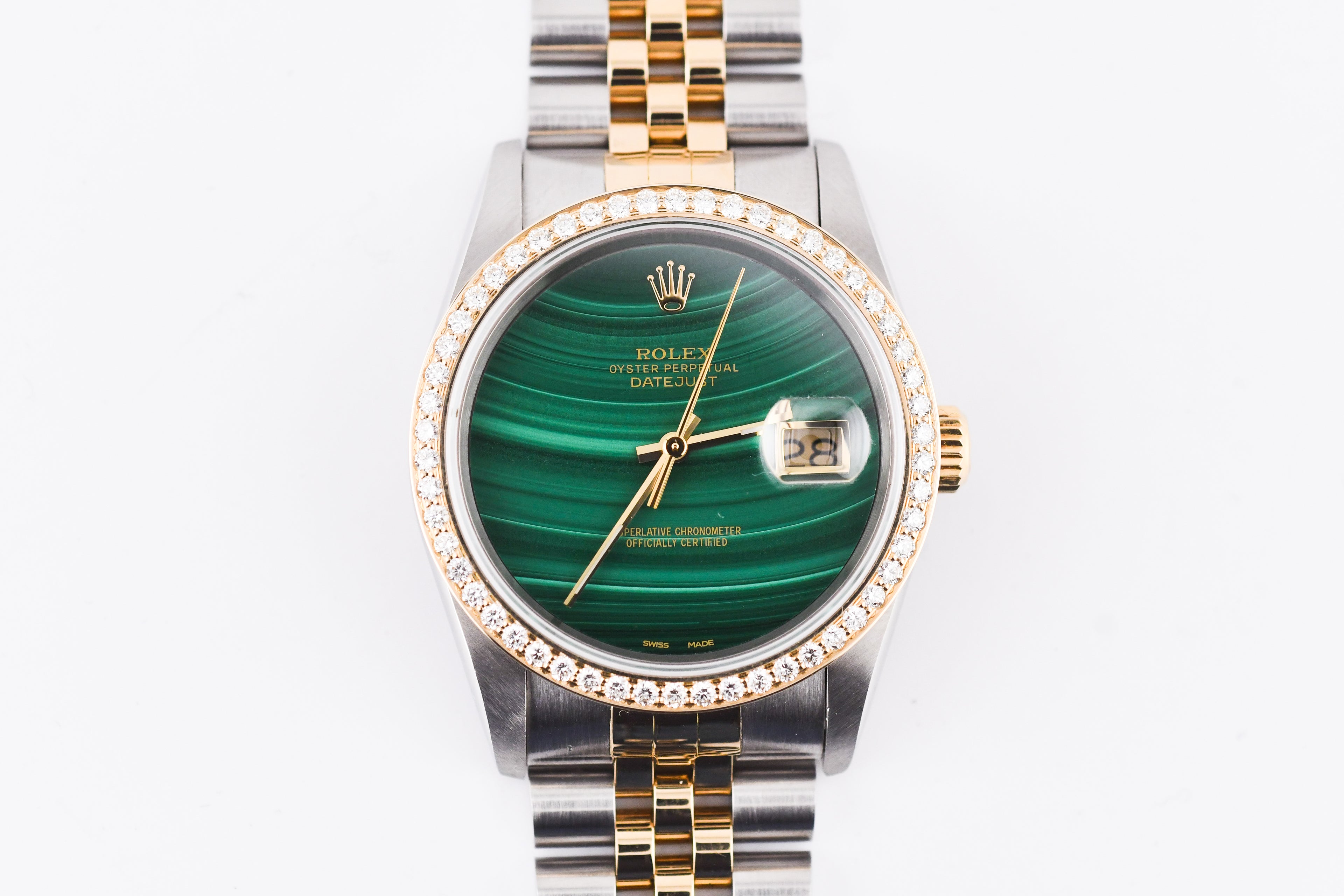 Luxury watch with green face and gold accents on a white background
