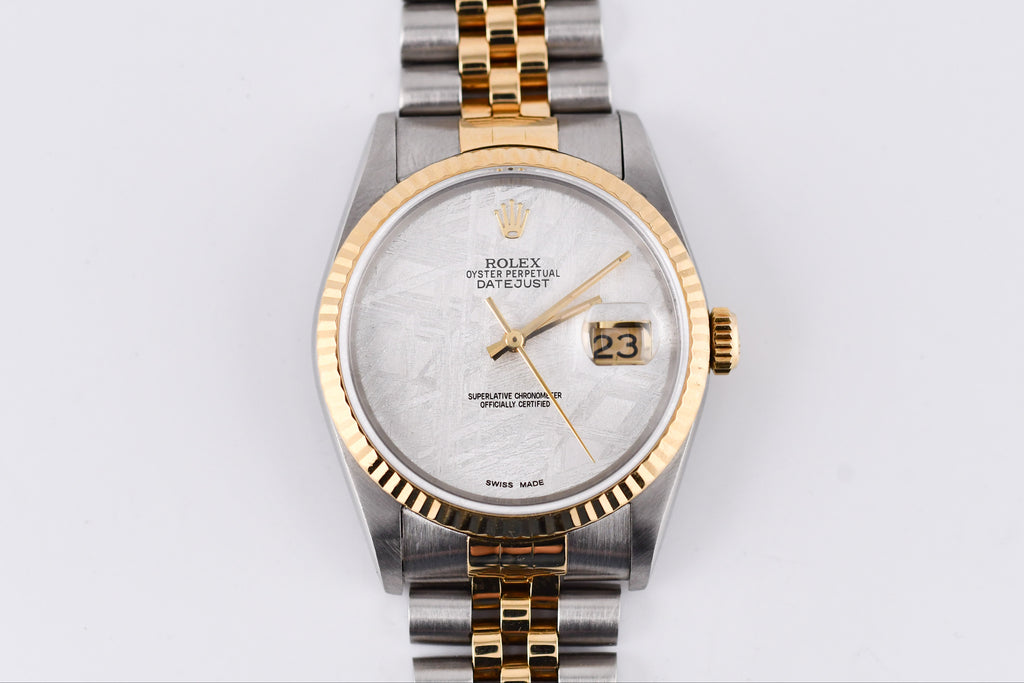 Rolex watch with two-tone metal band on a light gray background