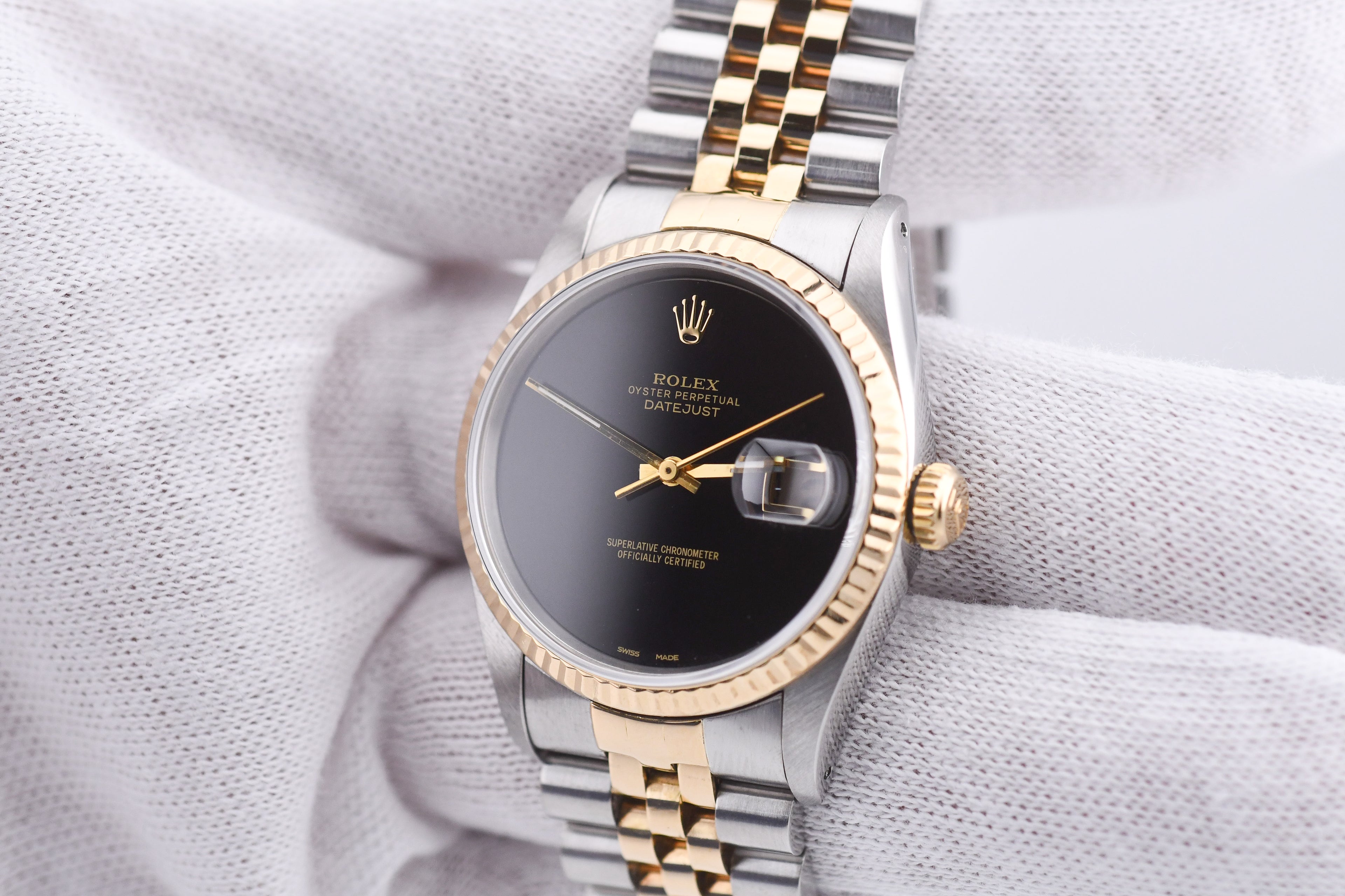 Luxury watch with black dial and gold accents on a textured white surface