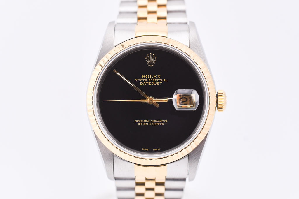 Rolex watch with black dial and gold and silver band on white background