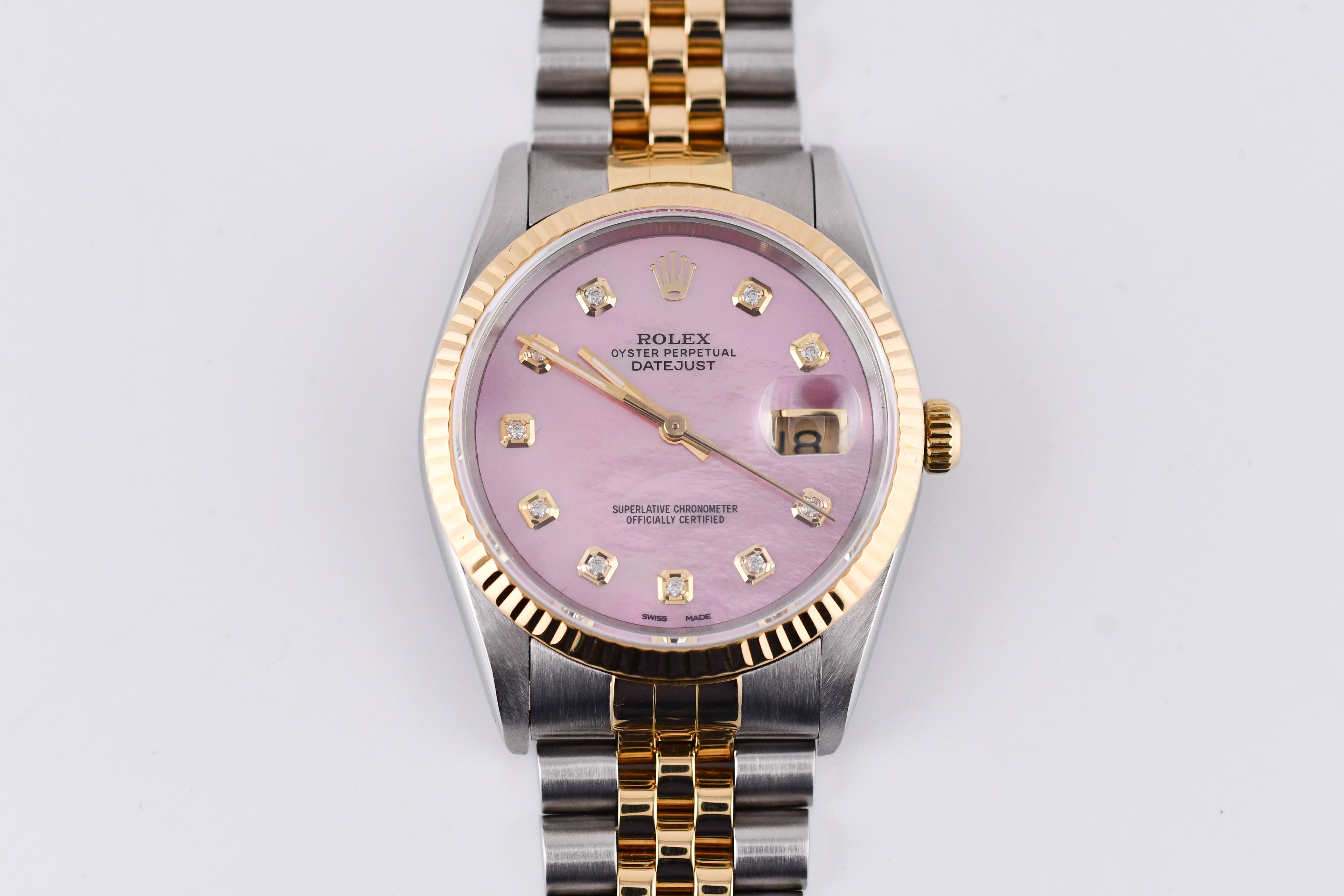 Rolex watch with pink dial and gold and silver band on a white background
